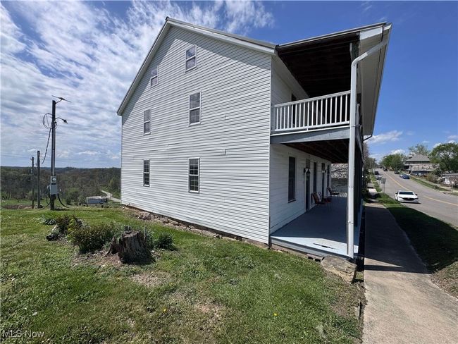 View of property exterior featuring a lawn, a balcony, and a patio | Image 23