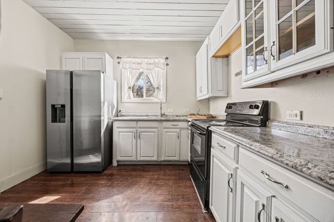 Kitchen with light stone counters, electric range, dark wood-type flooring, stainless steel fridge, and glass insert cabinets | Image 10