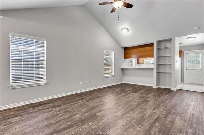 Unfurnished living room featuring a ceiling fan, high vaulted ceiling, and wood finished floors | Image 4