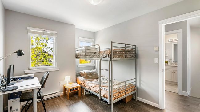 Bedroom featuring a baseboard radiator, wood finished floors, baseboards, and a sink | Image 22