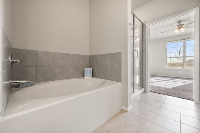 Bathroom featuring baseboards, tile patterned floors, a stall shower, a garden tub, and a ceiling fan | Image 9