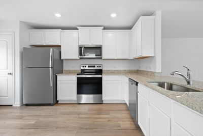 Kitchen includes granite countertops, luxury vinyl plank flooring, 36” upper cabinets with crown molding, a full suite of stainless-steel Whirlpool appliances – including refrigerator with ice maker, recessed lighting, and a large single basin sink. | Image 3