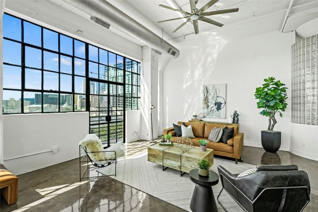 Living room featuring a ceiling fan, concrete floors, and a towering ceiling | Image 8