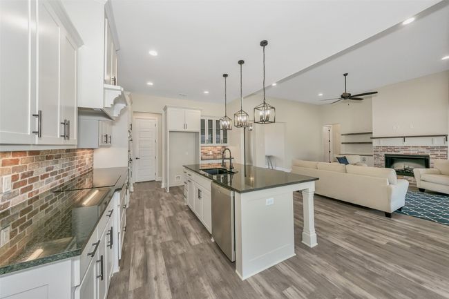 Kitchen with a ceiling fan, a sink, stainless steel dishwasher, wood finished floors, and a brick fireplace | Image 9