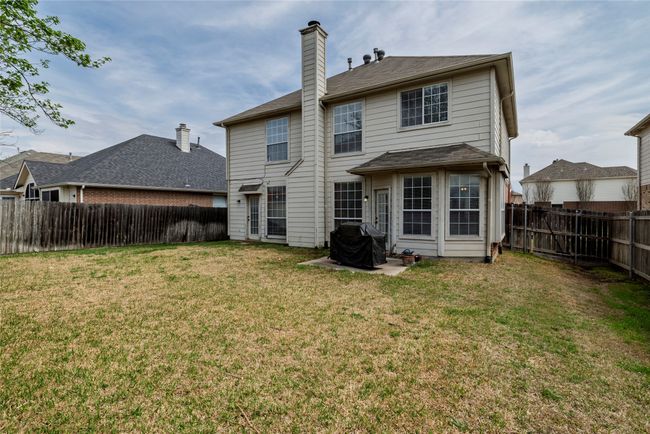 Rear view of house featuring a fenced backyard, a lawn, and a chimney | Image 33