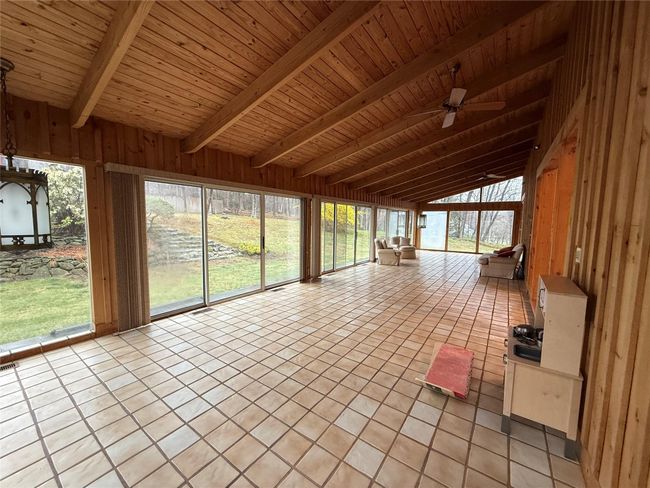 Unfurnished sunroom with beamed ceiling and a ceiling fan | Image 9
