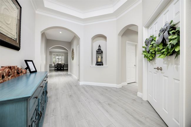 Welcoming foyer featuring arched walkways, chandelier, crown molding, and newly installed flooring. | Image 17