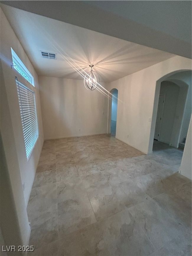Empty room with arched walkways and a chandelier | Image 4