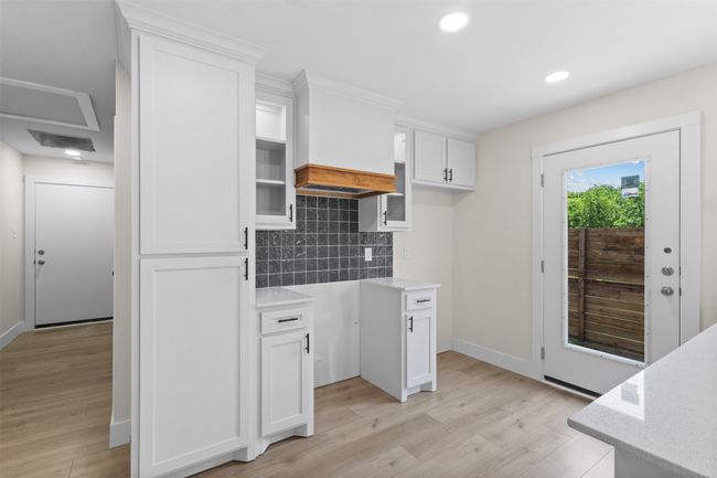 Kitchen with light wood-style flooring, tasteful backsplash, white cabinets, recessed lighting, and light stone counters | Image 16
