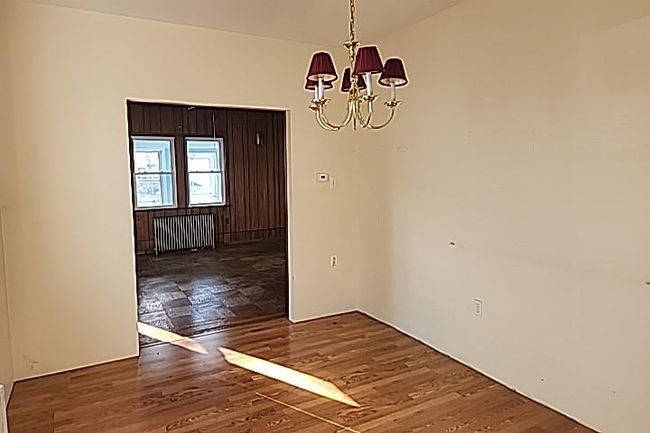Unfurnished dining area with a notable chandelier, dark hardwood / wood-style floors, and radiator | Image 7