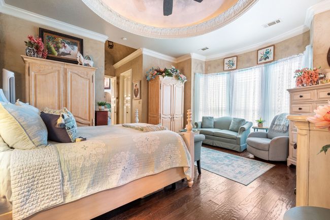 Bedroom featuring wood finished floors, ornamental molding, a raised ceiling, and a ceiling fan | Image 22