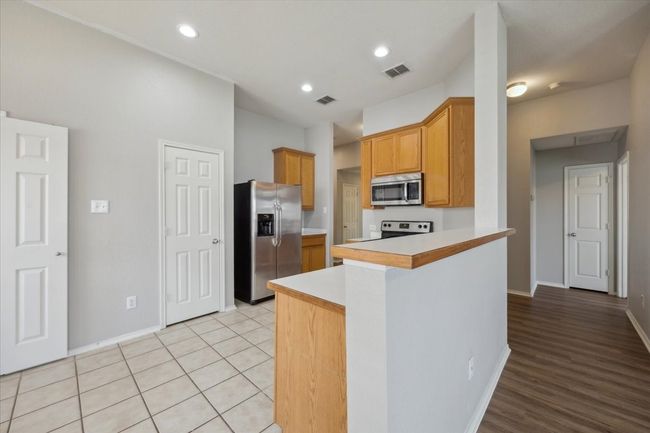 Kitchen with appliances with stainless steel finishes, light countertops, baseboards, a peninsula, and recessed lighting | Image 5