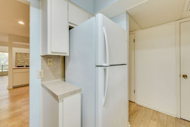 Kitchen with freestanding refrigerator, light wood-style flooring, white cabinetry, recessed lighting, and light countertops. | Image 9