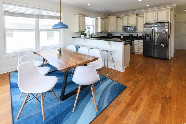 Kitchen featuring a peninsula, wood finished floors, appliances with stainless steel finishes, dark countertops, and crown molding | Image 5