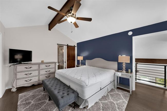 Bedroom featuring dark wood-style floors, a ceiling fan, a barn door, and connected bathroom | Image 7