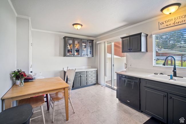 Kitchen featuring dishwasher, a sink, ornamental molding, decorative backsplash, and glass insert cabinets | Image 6