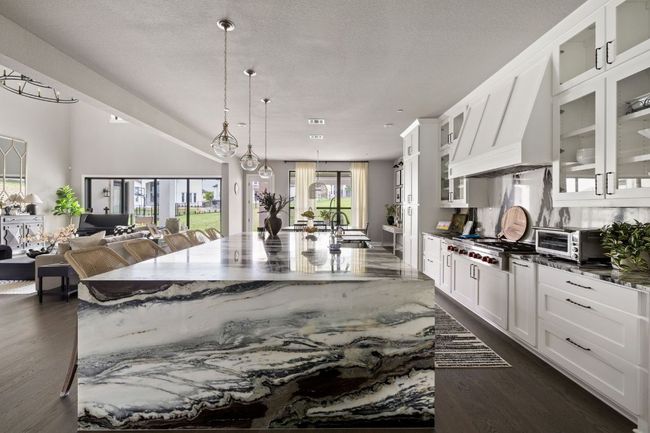Kitchen featuring white cabinetry, stainless steel gas cooktop, open floor plan, a toaster, and a spacious island | Image 7