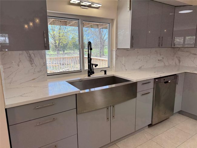 Kitchen with dishwasher, backsplash, gray cabinetry, and a sink | Image 4