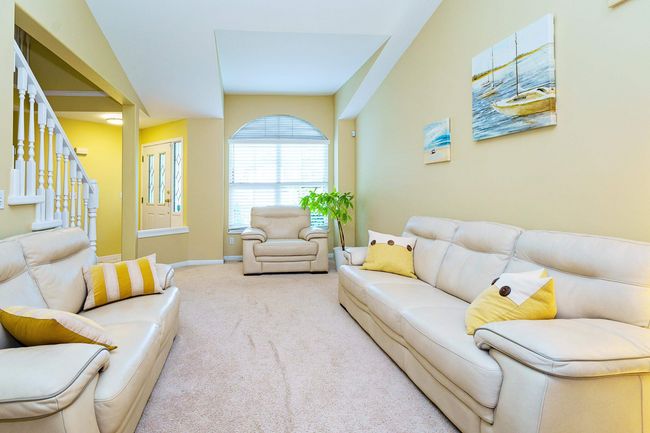 Carpeted living area featuring stairway and baseboards | Image 4