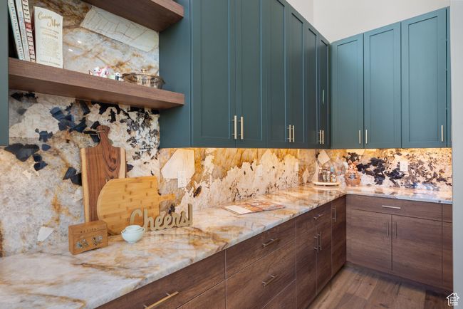 Kitchen featuring open shelves, decorative backsplash, light wood-style flooring, and light stone counters | Image 33