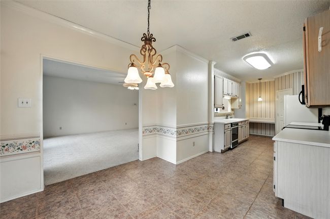 Kitchen featuring a chandelier, crown molding, light countertops, decorative light fixtures, and a textured ceiling | Image 18