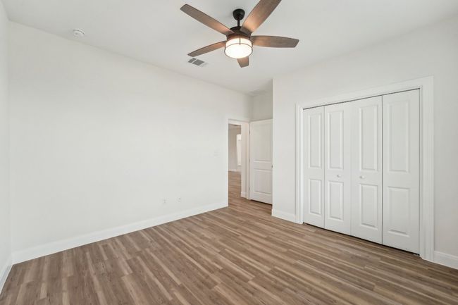 Bedroom 2 with wood plank vinyl floor, visible vents, a ceiling fan, a closet, and baseboards | Image 29