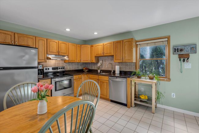Eat in kitchen featuring stainless steel appliances, ample cabinet space, decorative backsplash, light tile flooring, and granite countertops | Image 5