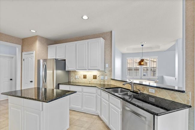 A breakfast bar overlooks the family room and sits conveniently next to the breakfast nook, creating a seamless flow for casual dining. | Image 13