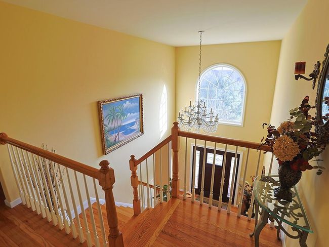 Foyer with baseboards, a high ceiling, wood finished floors, and a chandelier | Image 22