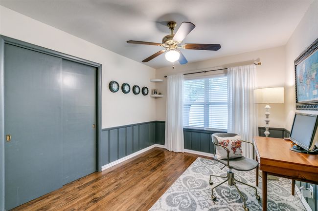 Middle bedroom currently used as an office has wood finished floors, ceiling fan, and wainscoting | Image 18