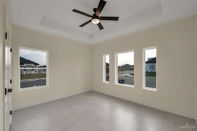 Empty room featuring a raised ceiling, baseboards, a ceiling fan, and light tile patterned flooring | Image 17