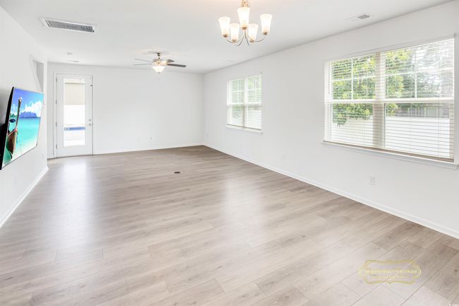 Empty room with a ceiling fan, a chandelier, light wood-type flooring, and baseboards | Image 15