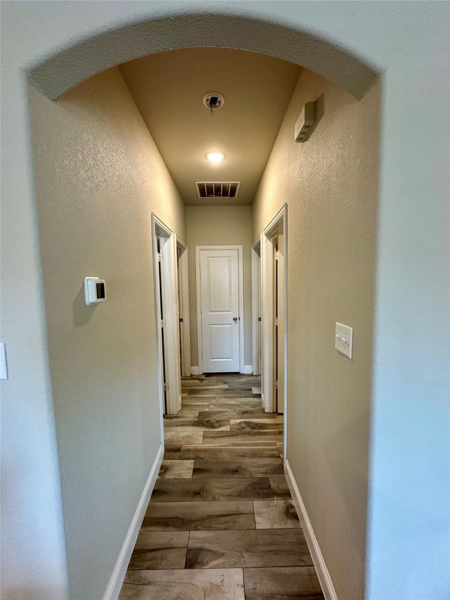 Hallway featuring arched walkways, wood finished floors, and a textured wall | Image 28