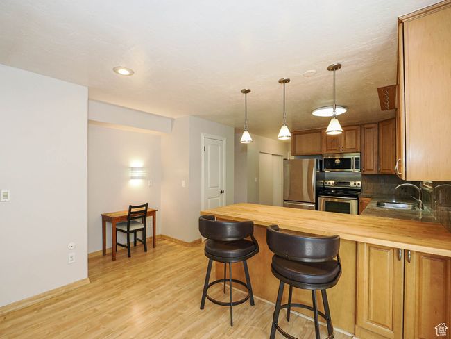 Kitchen with stainless steel appliances, butcher block counters, a sink, a peninsula, and recessed lighting | Image 9