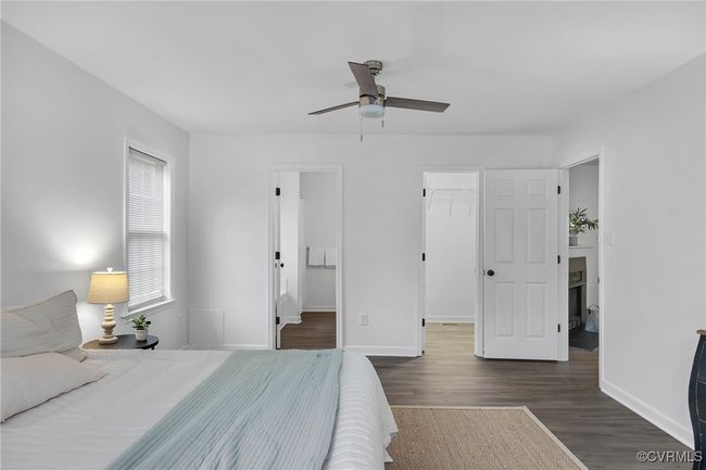 Bedroom with wood finished floors, a walk in closet, baseboards, a closet, and ceiling fan | Image 12