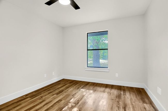Spare room featuring wood finished floors, baseboards, and ceiling fan | Image 16