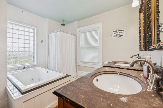 Bathroom featuring a tub with jets, double vanity, and a shower with shower curtain | Image 31