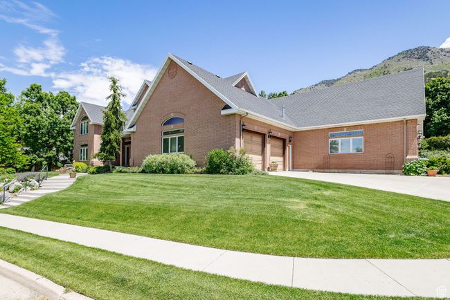 View of front facade featuring brick siding, an attached garage, a front yard, concrete driveway, and a mountain view | Image 73