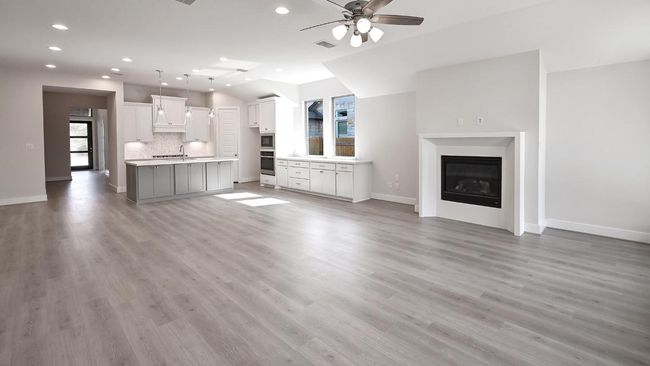 Unfurnished living room with light wood finished floors, a ceiling fan, recessed lighting, and a glass covered fireplace | Image 21