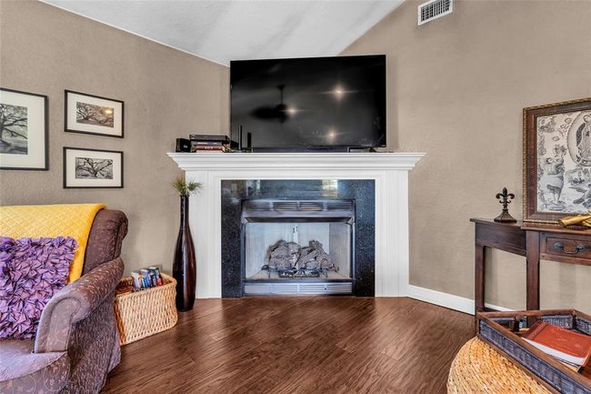 Living area featuring wood finished floors, a fireplace, vaulted ceiling, and baseboards | Image 5