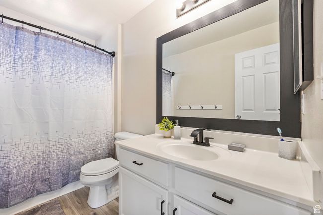 Full bathroom featuring wood finished floors, vanity, a shower with shower curtain, and toilet | Image 26