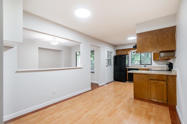 Kitchen with black appliances, brown cabinets, and light wood-style flooring | Image 12