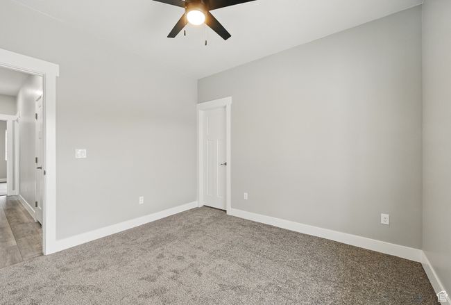 Carpeted empty room with a ceiling fan and baseboards | Image 44