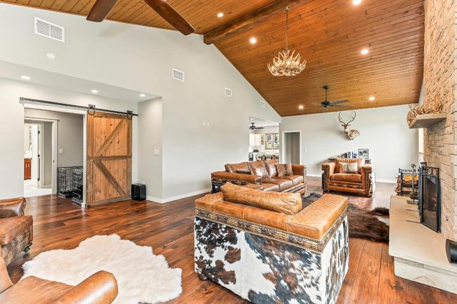 Living room with ceiling fan, wooden ceiling with exposed beams, high vaulted ceiling, a barn door, and wood-type​​‌​​​​‌​​‌‌​‌‌​​​‌‌​​‌‌​‌​​​​​‌ flooring | Image 6