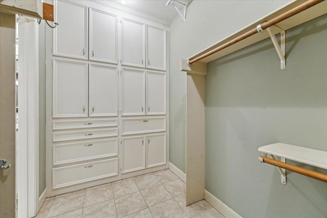 The primary closet includes a wall of built-in cabinets, drawers, and double wide hamper. | Image 22
