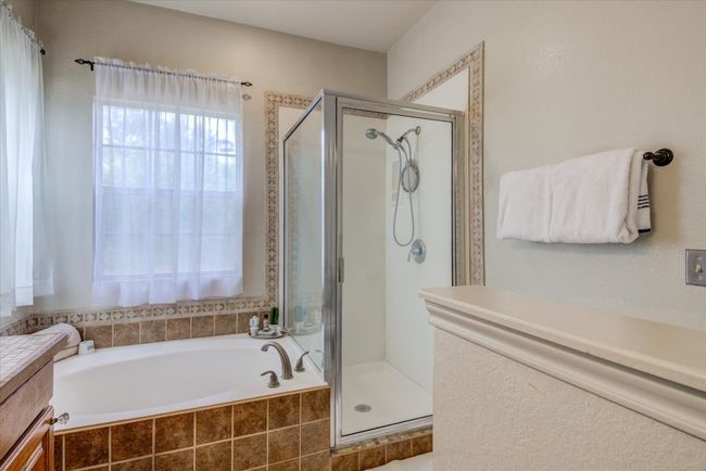 Primary bathroom soaking tub with a view of the back deck. | Image 12