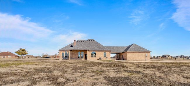 Back of house with brick siding, a chimney, and a shingled roof | Image 35