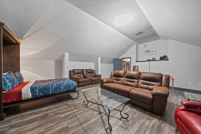 Home theater featuring a textured ceiling, visible vents, vaulted ceiling, and wood finished floors | Image 27