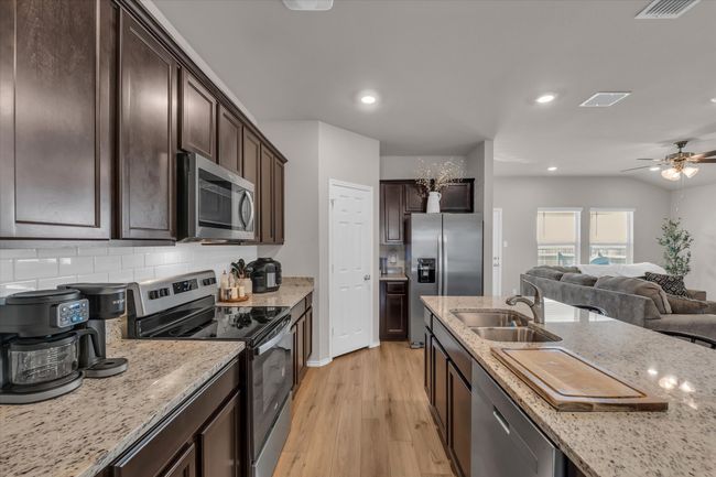 Kitchen with appliances with stainless steel finishes, a sink, light wood-type flooring, dark brown cabinets, and recessed lighting | Image 21
