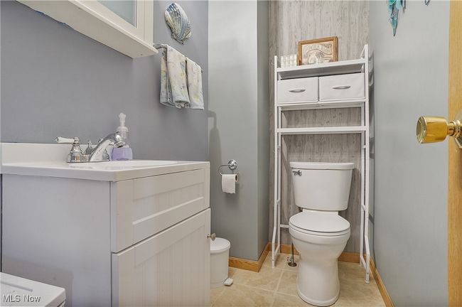 Half bathroom featuring tile patterned floors, baseboards, toilet, and vanity | Image 24